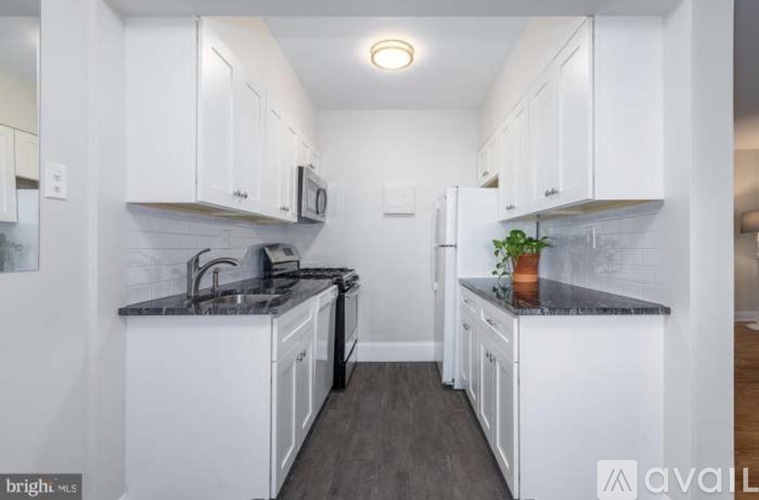 A kitchen with white cabinets and a black countertop.