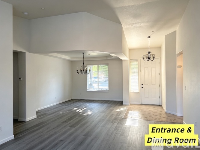 A spacious entrance and dining room with a chandelier and a window.