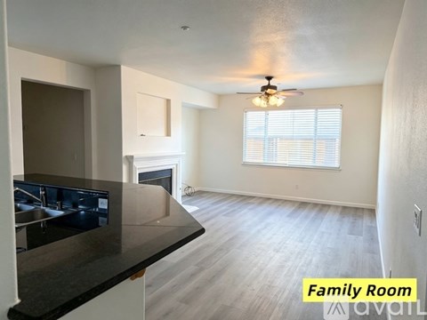 A spacious family room with a fireplace and a kitchen area in the background.