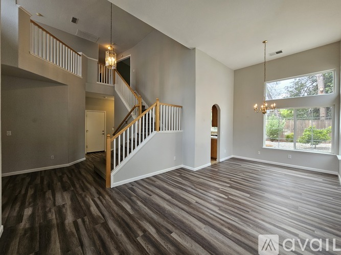 A spacious living room with wood flooring and a staircase.