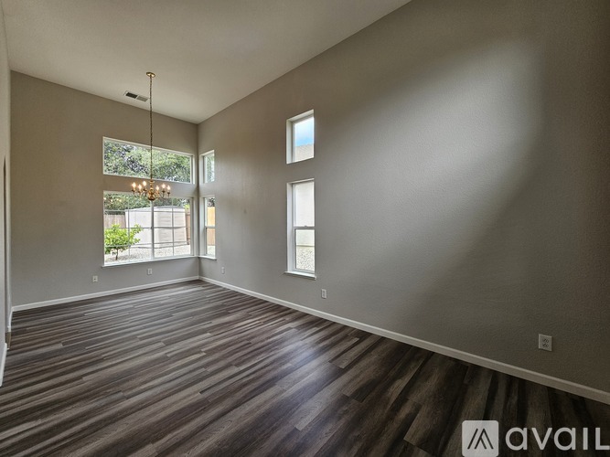 A spacious room with wooden flooring and large windows.