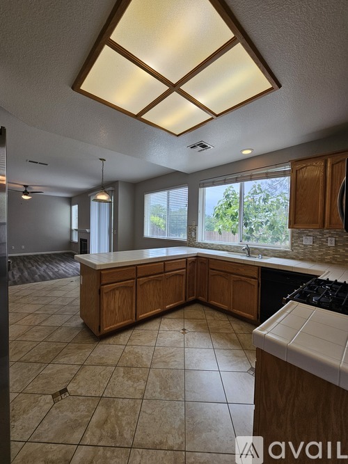 A kitchen with tile flooring and wooden cabinets is available for rent.