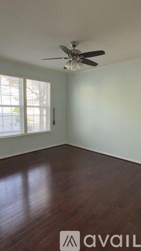 A room with a ceiling fan and wooden flooring.