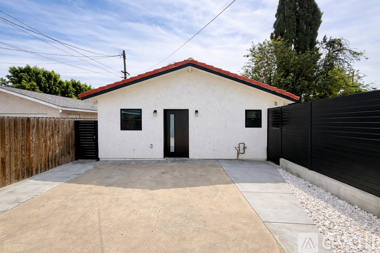 A white house with a red roof and a black fence.