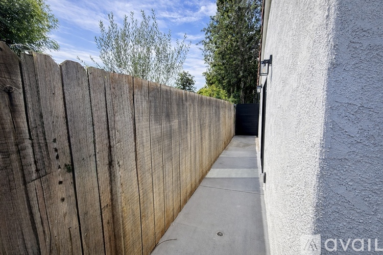 A wooden fence runs along the side of a white building.