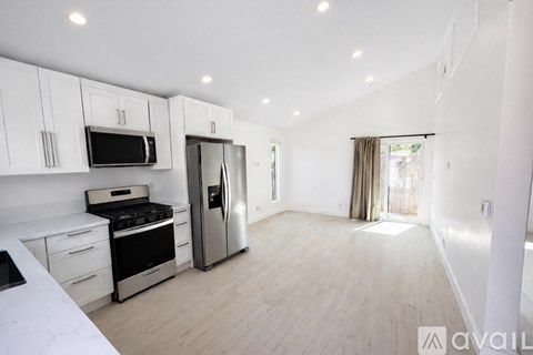 A kitchen with white cabinets and a stainless steel refrigerator.