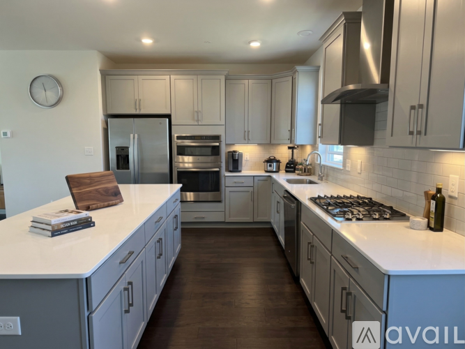 A modern kitchen with a white countertop and stainless steel appliances.