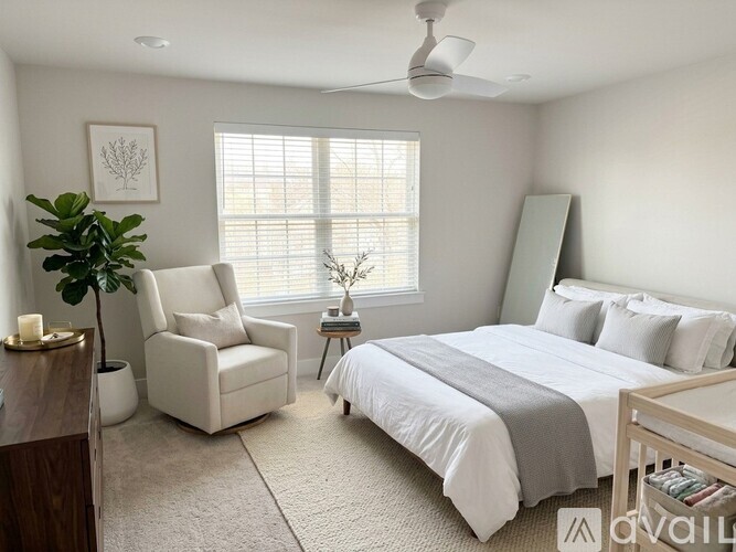 A bedroom with a bed, chair, and plant.