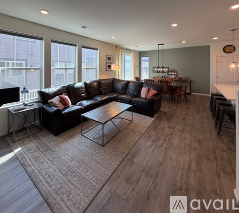 A living room with a black leather couch and a wooden coffee table.
