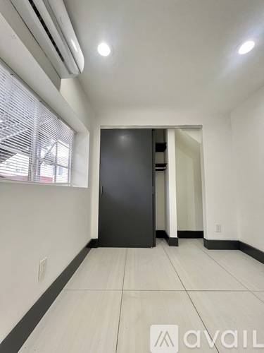 A room with a black door and a window with blinds.