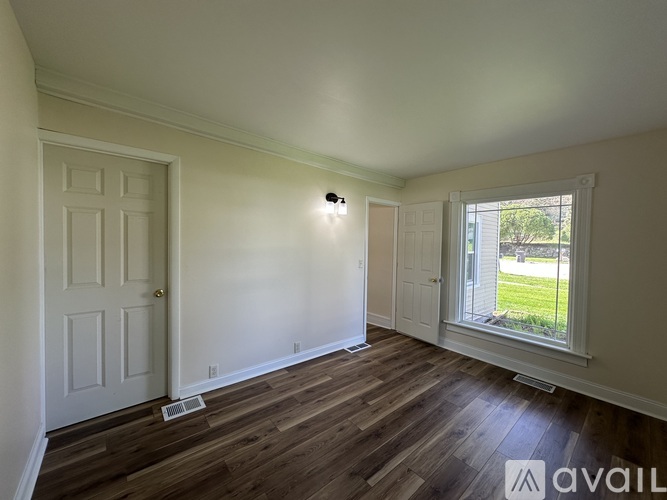 A room with a door, window, and wooden flooring.