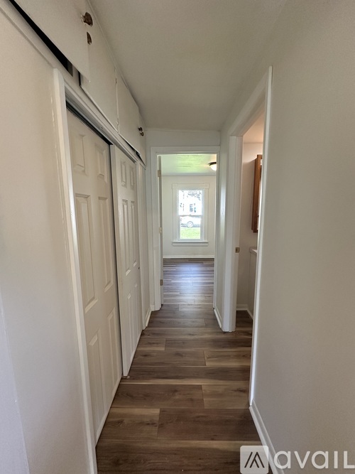 A long hallway with white walls and wood flooring.
