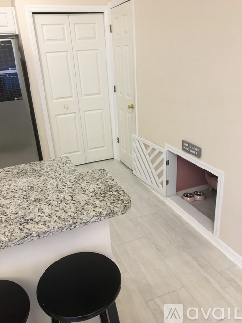 A kitchen with a granite counter top and a small black stool.