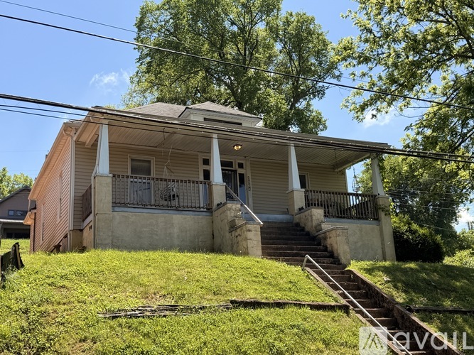 A house with a porch and a tree in front of it.