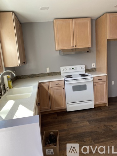 A kitchen with a white stove and wooden cabinets.