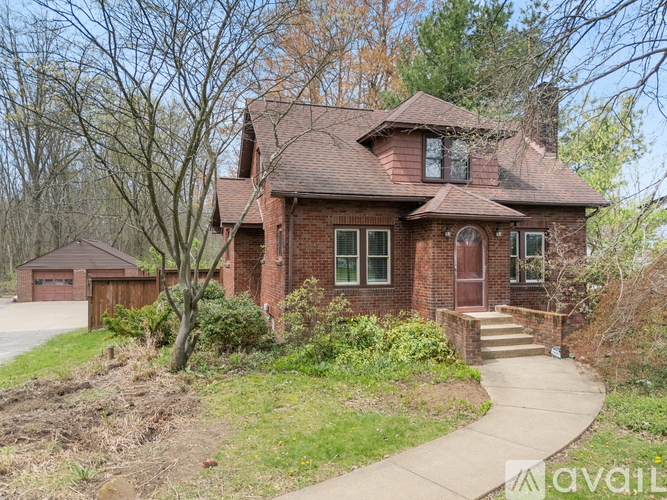 A red brick house with a brown roof and a small porch.