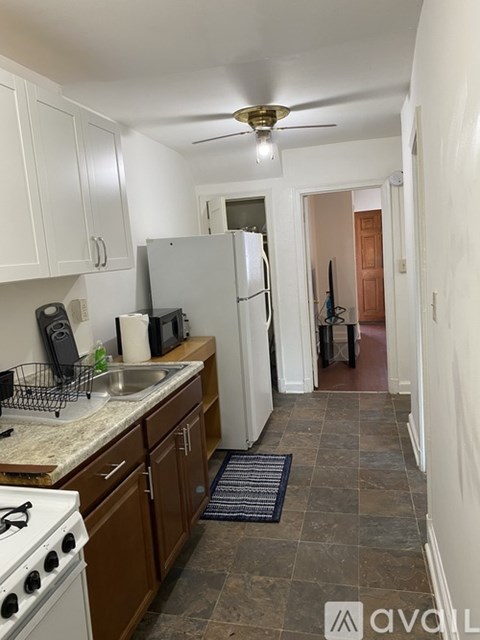 A kitchen with white cabinets and a black mat on the floor.