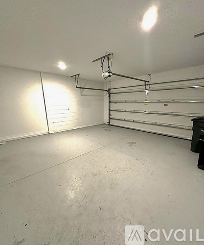 A spacious garage with a white floor and walls, and a black object on the right side.