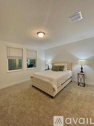 A bedroom with a large bed and two lamps.