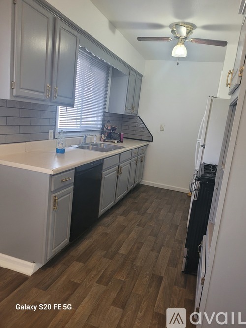 A kitchen with a white counter top and wooden floors.