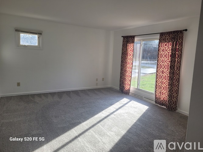 A room with a carpeted floor and a window with curtains.