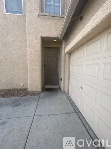 A white garage door is on the right side of a concrete walkway.