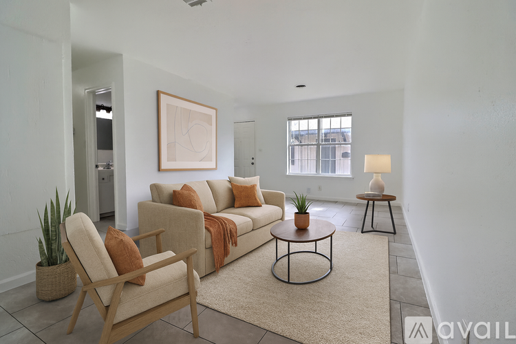 A living room with a beige couch, a chair, and a rug.