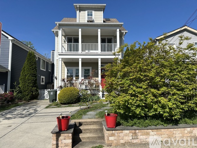 A house with a white porch and a red bucket on the steps.