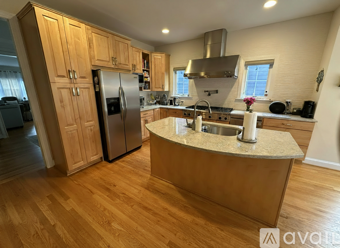 A kitchen with wooden cabinets and a marble island.