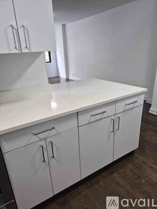 A white kitchen with wooden floors and white cabinets.