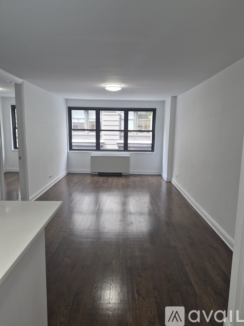 A room with wooden floors and a window with blinds.