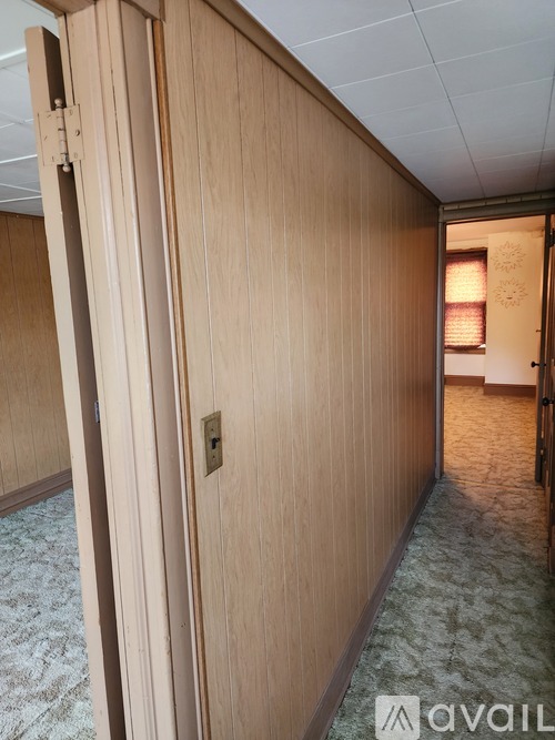 A hallway with a carpeted floor and wooden walls.