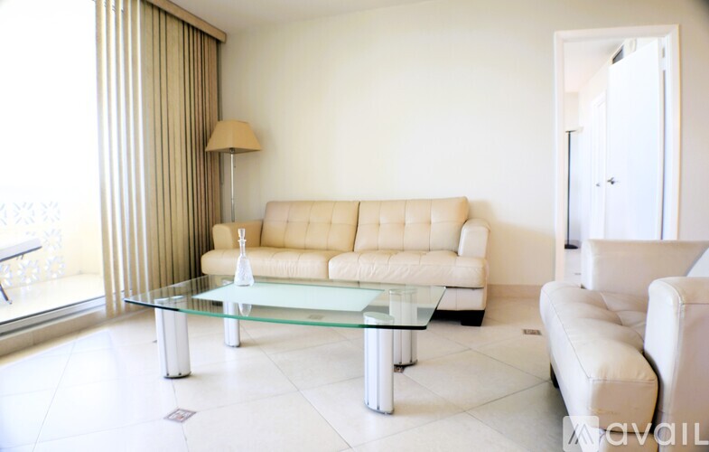 A living room with a glass table and a white sofa.