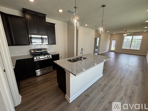 A kitchen with black cabinets and a granite countertop.