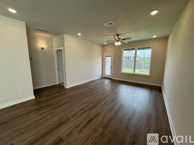 A spacious room with wood flooring and a ceiling fan.