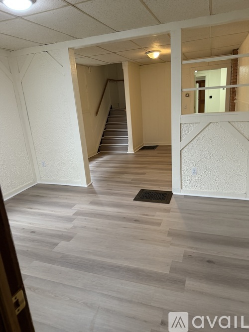A hallway with a staircase and a white wall.