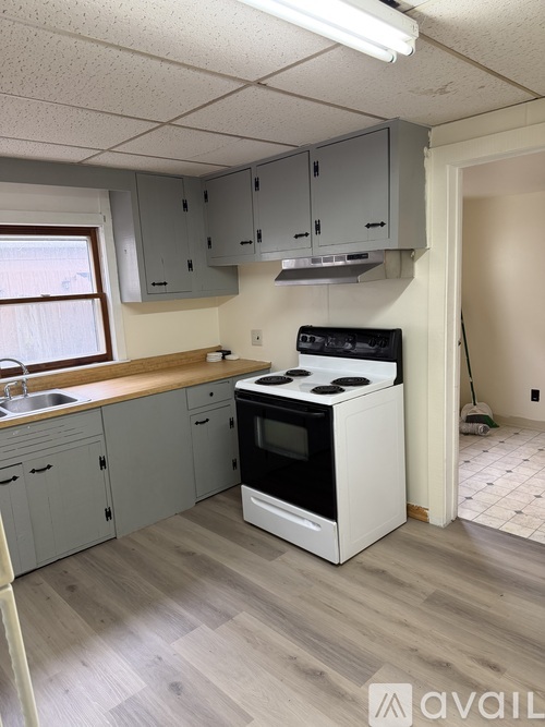 A kitchen with a white stove top oven and grey cabinets.