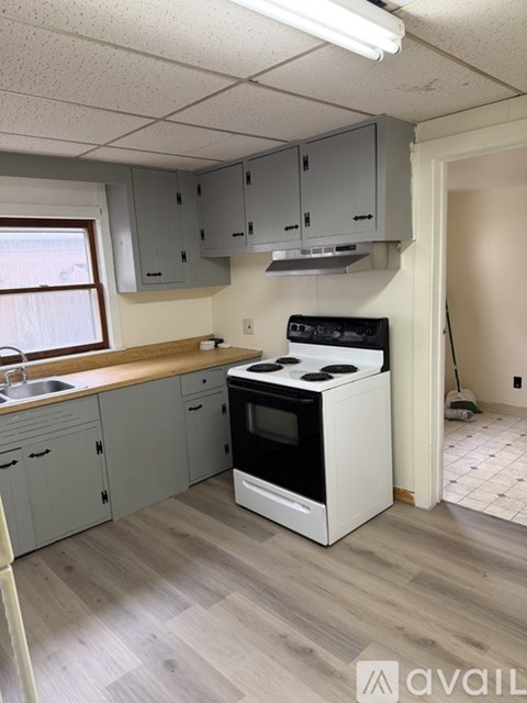 A kitchen with a white stove top oven and grey cabinets.