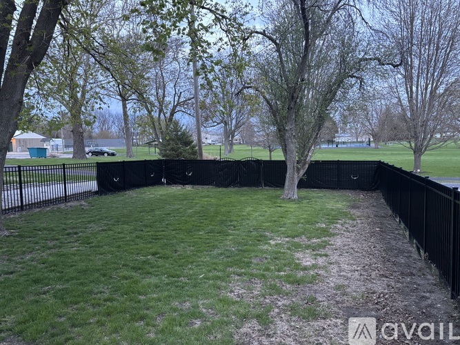 A black fence encloses a grassy area with trees.