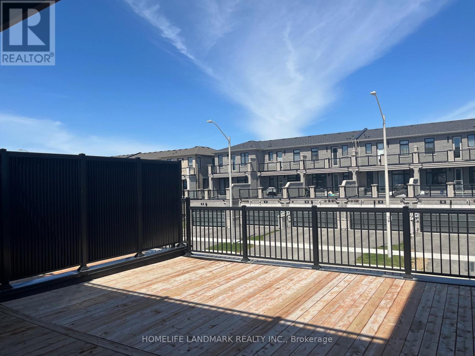 A wooden deck with a metal fence in front of a building.