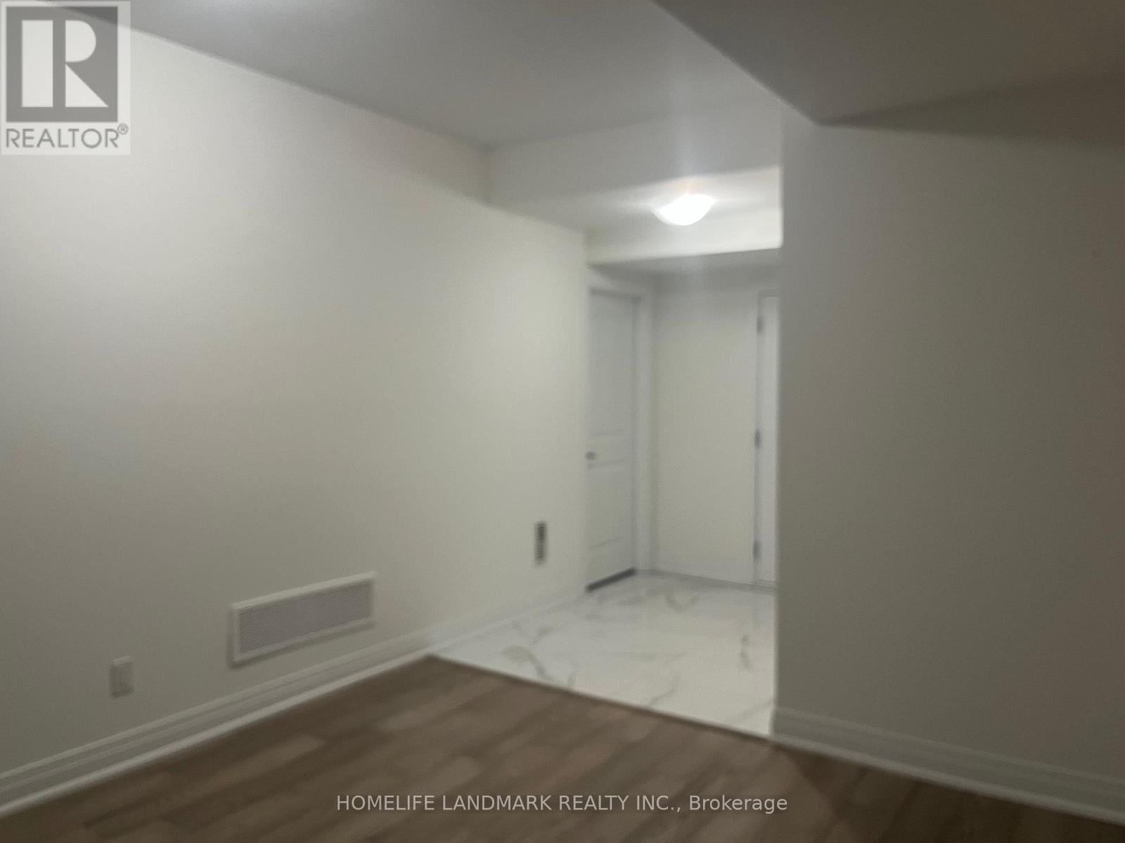 A room with a white wall and a doorway leading to another room.