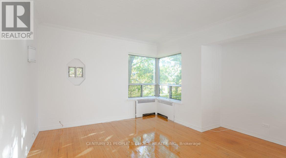 A room with a wooden floor and a window overlooking a garden.