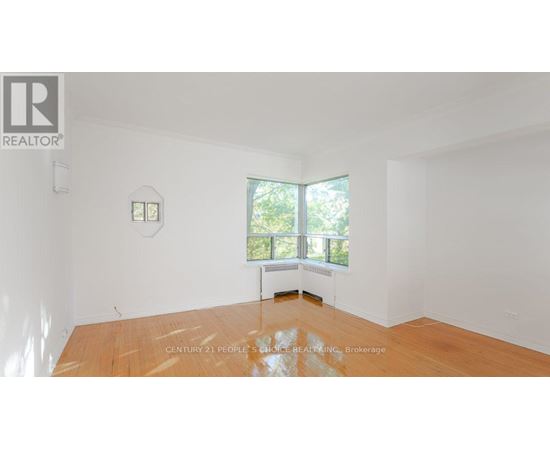 A room with a wooden floor and a window overlooking a garden.
