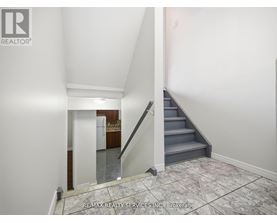 A hallway with a staircase leading to a kitchen.
