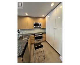A modern kitchen with a granite countertop and stainless steel appliances.