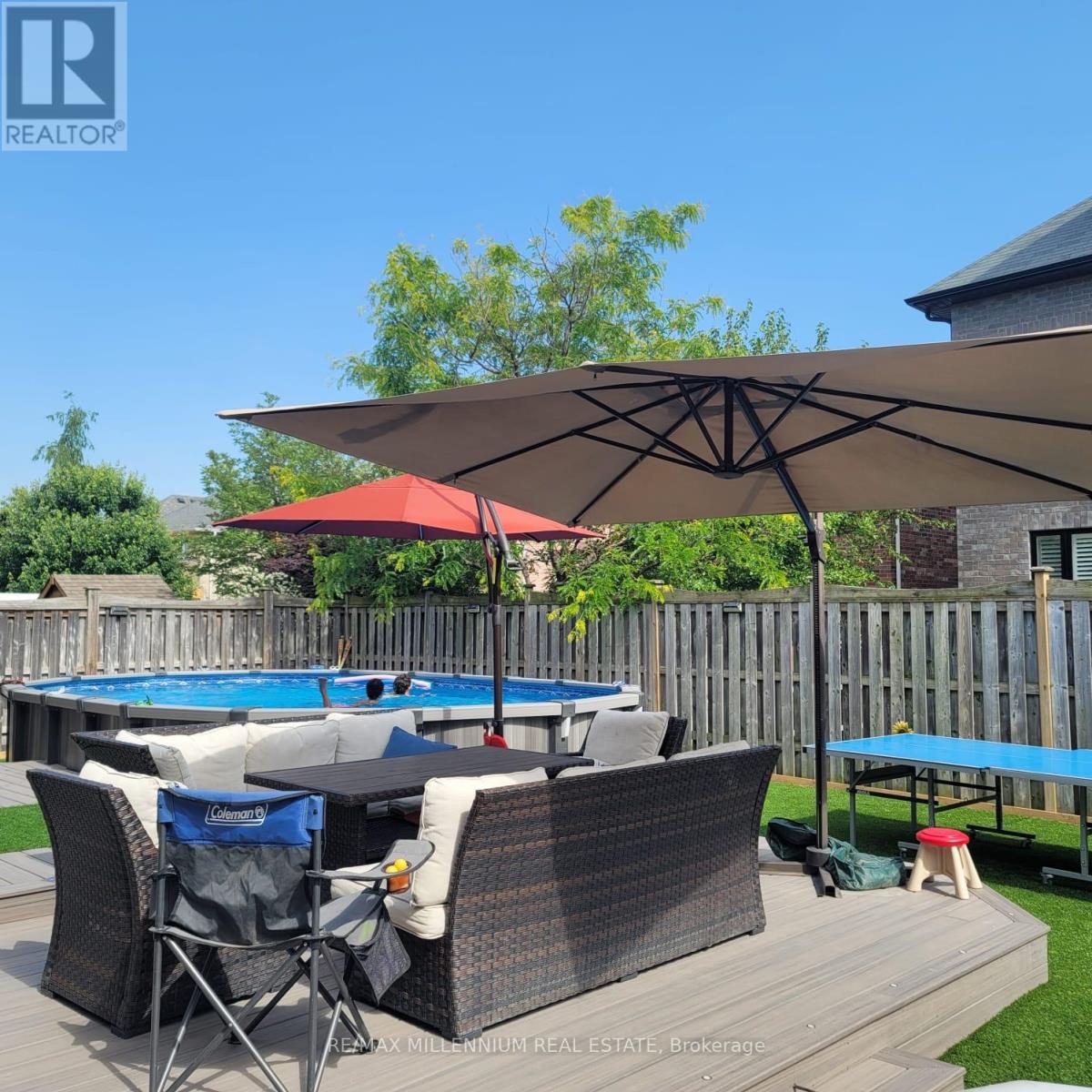 A pool table with chairs and an umbrella in a backyard.