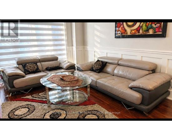 A living room with a glass coffee table and two grey couches.