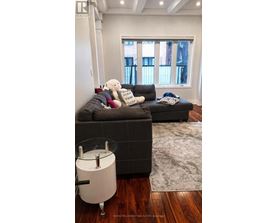 A living room with a grey couch and a white bear on it.