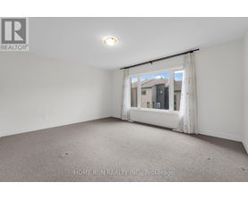 A room with a carpeted floor and a window with a view of buildings outside.