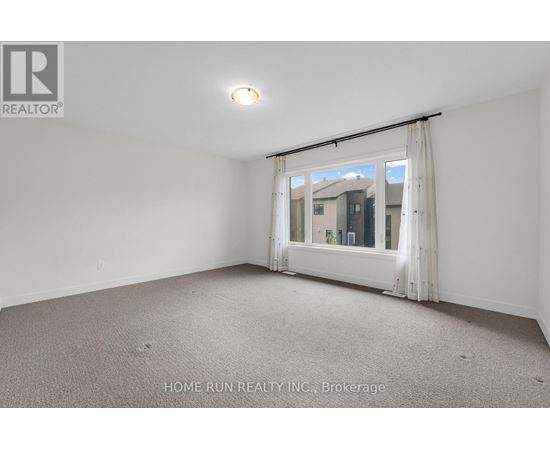 A room with a carpeted floor and a window with a view of buildings outside.